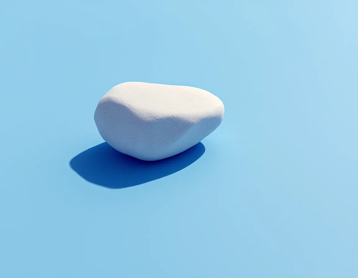 A single smooth boulder resting in open sky-blue space